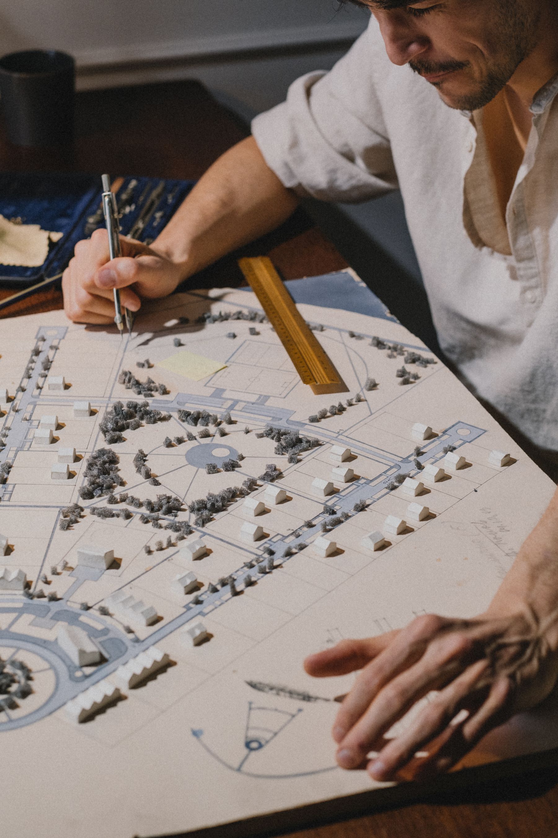An architect works by hand on a detailed landscape model and drawing